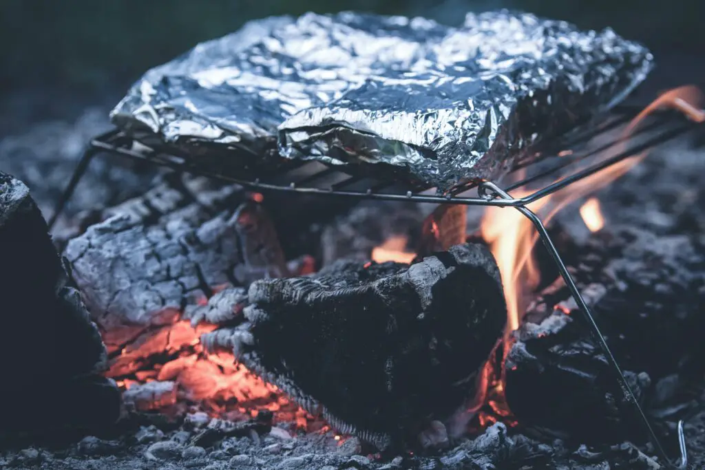 Foil packets being cooked over an open campfire.
