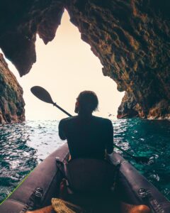 kayaker kayaking through an ocean cave on an inflatable kayak